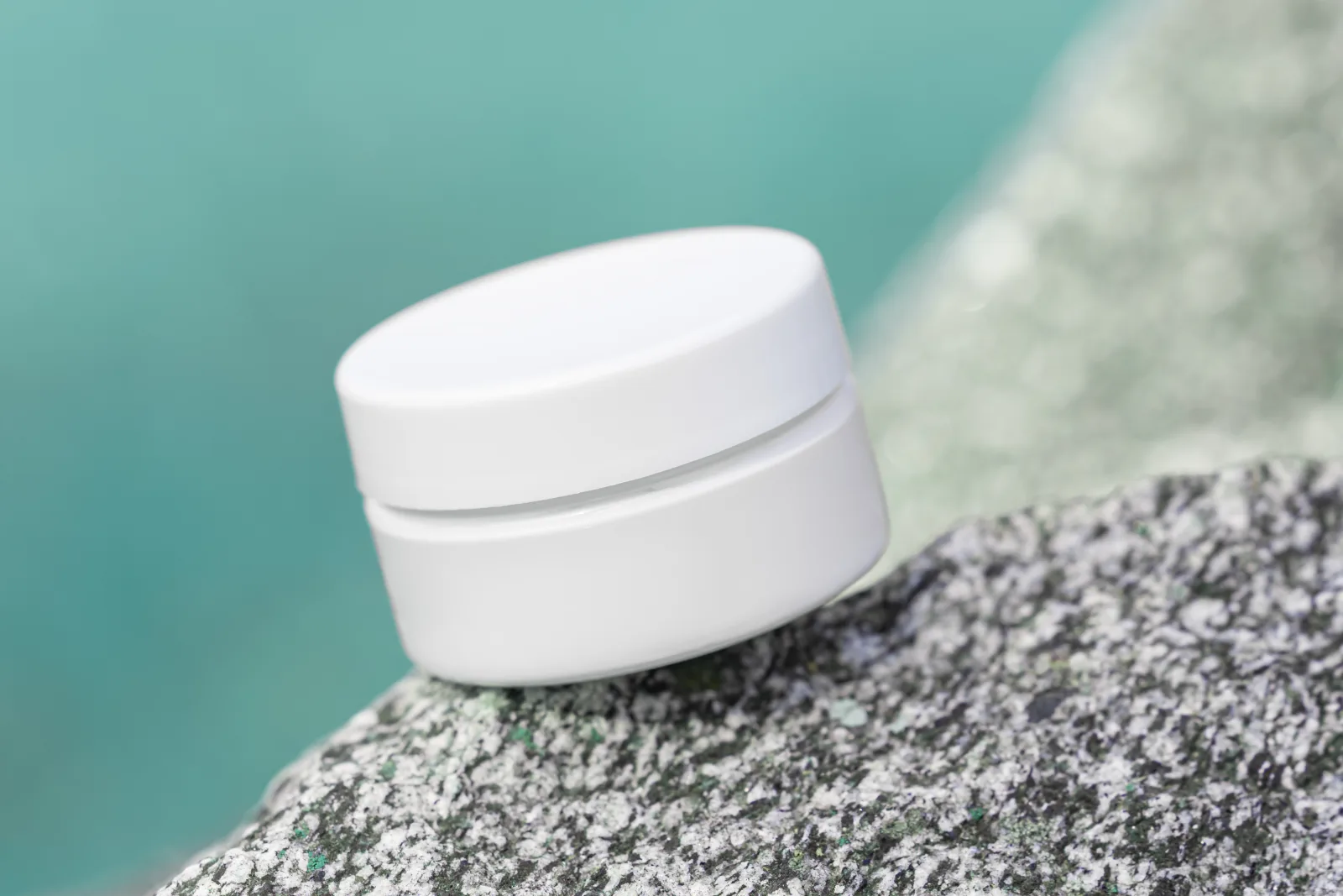 Jar of topical lotion on a stone surface